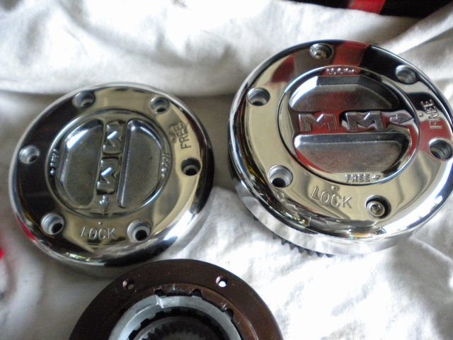 Two chrome MM manual locking hub dials marked LOCK and FREE, with a splined hub gear on a white cloth