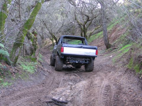 1989 Ford Bronco - This lifted 1989 Ford Bronco navigates a challenging muddy trail through a wooded area.