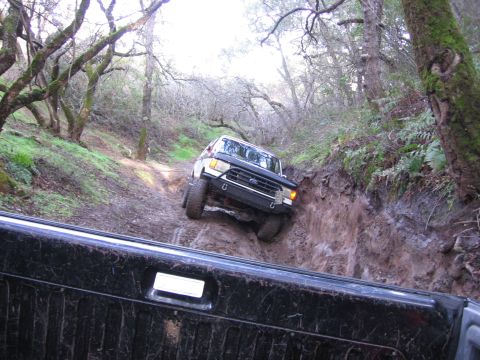 1989 Ford Bronco - This 1989 Ford Bronco is tackling a challenging muddy incline on a wooded trail.