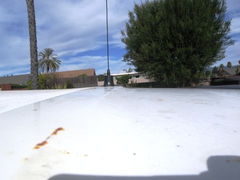 1986 Ford Bronco - The photo shows the roof of a vehicle with an antenna, against a backdrop of trees and sky.