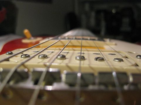 1989 Mazda MX-6 - The image shows a close-up view of the strings and bridge pickup on an electric guitar.