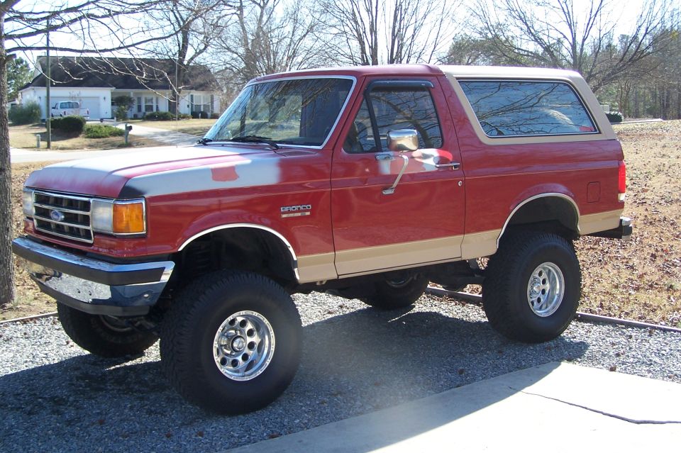Red and tan lifted Ford Bronco parked in a residential driveway