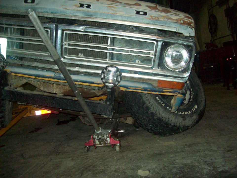 1971 Ford F-100 front end, grille, and headlight with a jack under the bumper
