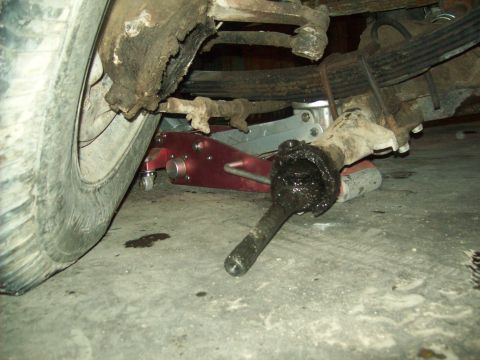1971 Ford F-100 - Close-up of the front suspension and wheel assembly of a 1971 Ford F-100, with a jack supporting the vehicle.