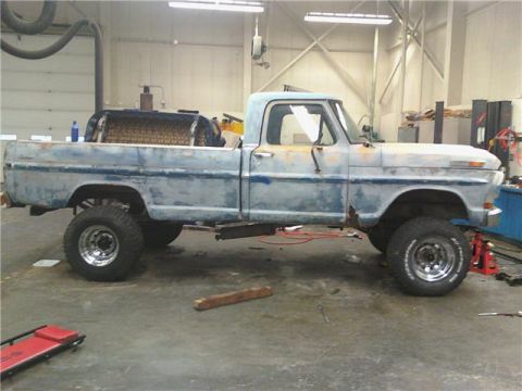 1971 Ford F-100 - Side view of a 1971 Ford F-100 pickup truck undergoing modifications in a garage setting.