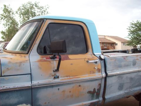 1971 Ford F-100 - This weathered pickup truck shows significant rust and paint wear, with a two-tone blue and tan exterior.