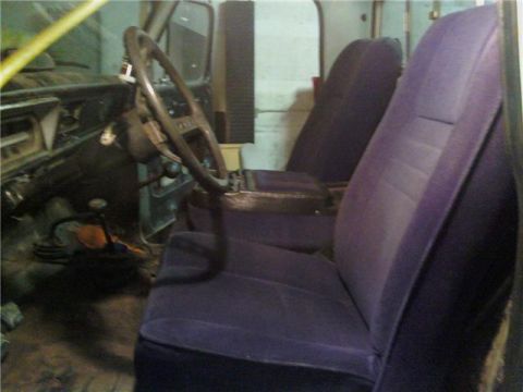 1971 Ford F-100 - The interior of a truck shows a steering wheel, gear shift, and two rows of purple seats.