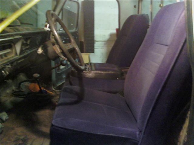Interior view of a truck, showing the steering wheel, dashboard, and purple seats