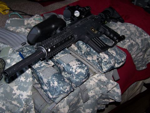 1986 Ford Bronco - A paintball gun and tactical gear are laid out on a bed, ready for use.