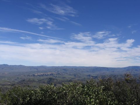 1989 Ford Bronco - A scenic view of rolling hills and mountains under a vast blue sky with wispy clouds.