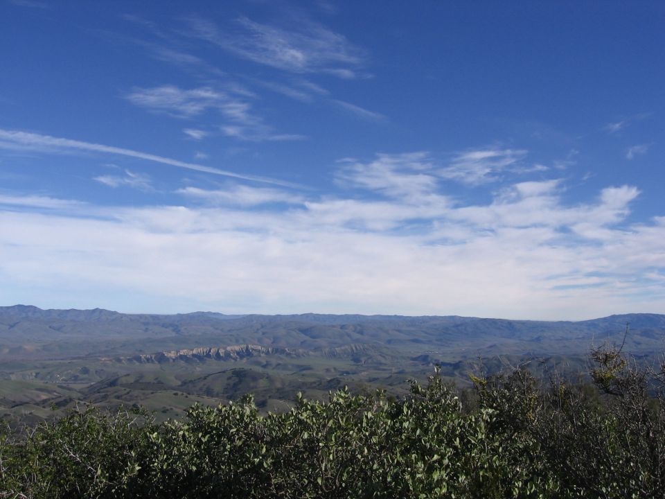 Hilly landscape under a blue sky with scattered clouds