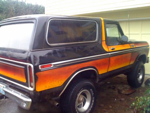 1978 Ford Bronco - This classic Ford Bronco features a distinctive two-tone paint job with orange and yellow gradient stripes along the side.