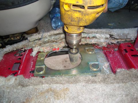 1993 Ford Taurus - A drill with a rotary file bit is used to enlarge an opening in the floor pan of a vehicle's interior.