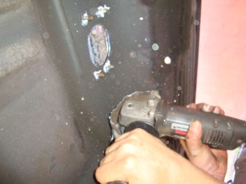1993 Ford Taurus - A person is using an angle grinder to cut a hole in a dark metal surface, with sparks flying.