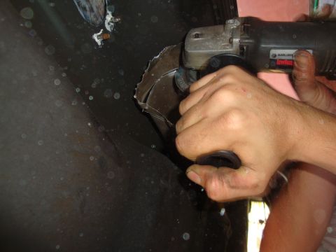 1993 Ford Taurus - A person uses an angle grinder to cut into a dark, curved metal surface.