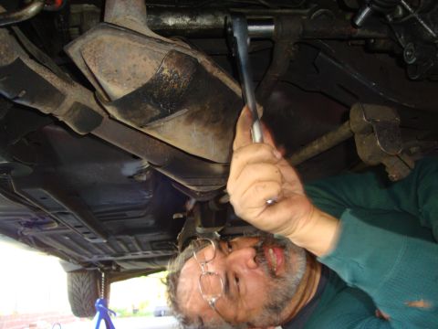 1993 Ford Taurus - Underneath view of a person performing maintenance on a vehicle's exhaust.