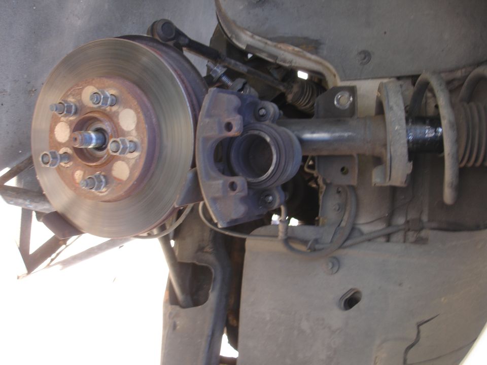 Close-up of a car's front suspension and brake rotor with caliper removed