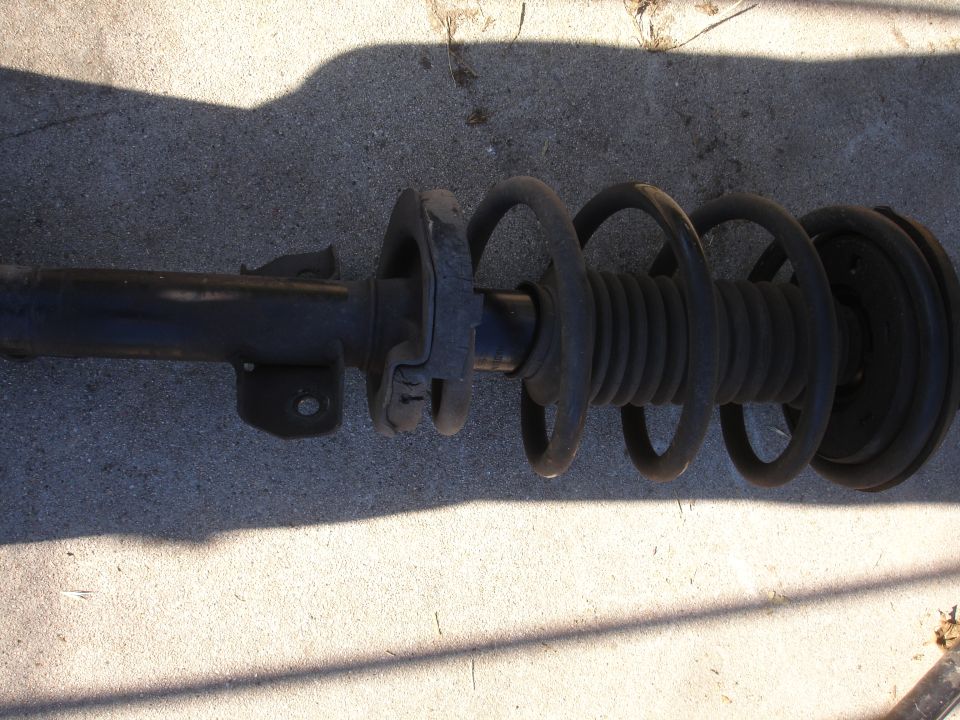 Car suspension strut with coil spring, lying on concrete