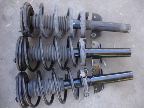 1992 Ford Taurus - Three suspension struts are shown side-by-side on a gray surface.