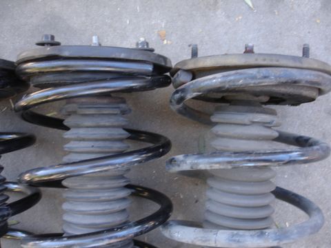 1992 Ford Taurus - A close-up view of two automotive suspension struts and their coiled springs.