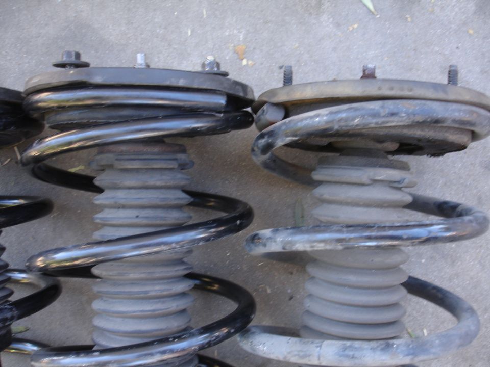 Two car suspension struts with coiled springs are shown side-by-side