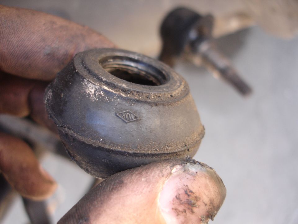 Rubber suspension part with NOK logo held by dirty hands