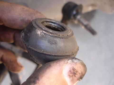 1992 Ford Taurus - A dirty suspension bushing with a NOK logo is held for inspection.