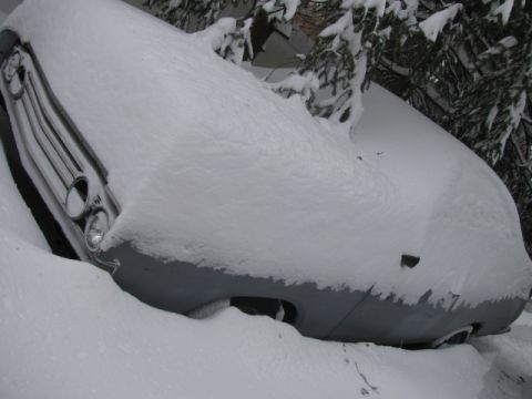 1969 Ford Torino - A 1969 Ford Torino is buried in snow, with only its front grille and headlights visible.
