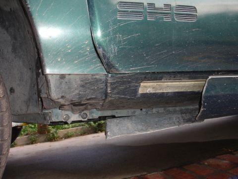 1995 Ford Taurus - Close-up of a green vehicle's side panel, revealing the 'SHO' emblem and signs of wear.