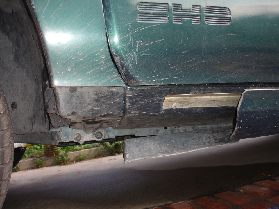 Green car side panel with 'SHO' badge, showing scratches and dirt