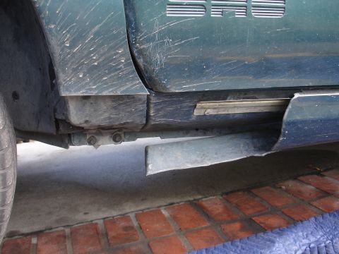 1995 Ford Taurus - A close-up view of a damaged green car door and undercarriage, with visible mud and scratches.