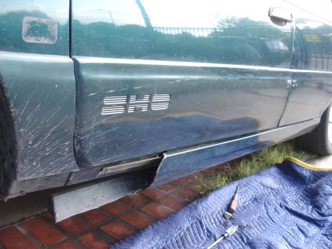 1995 Ford Taurus - Side view of a green 1995 Ford Taurus with an SHO emblem visible on the lower door panel.