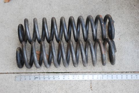 1996 Ford Bronco - Two dark coil springs are shown on a concrete surface next to a ruler. The Supermotors logo is visible in the lower right corner.