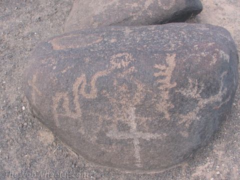1996 Ford C-350 (Centurion Conversions) - Ancient petroglyphs etched into a large dark rock, depicting various figures and abstract designs.