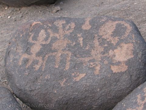 1996 Ford C-350 (Centurion Conversions) - Ancient petroglyphs are etched into the surface of a dark rock, displaying intricate patterns and figures.