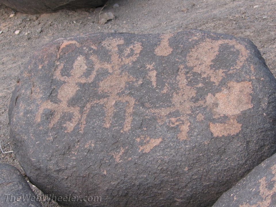 Petroglyphs on a dark rock surface with lighter brown markings