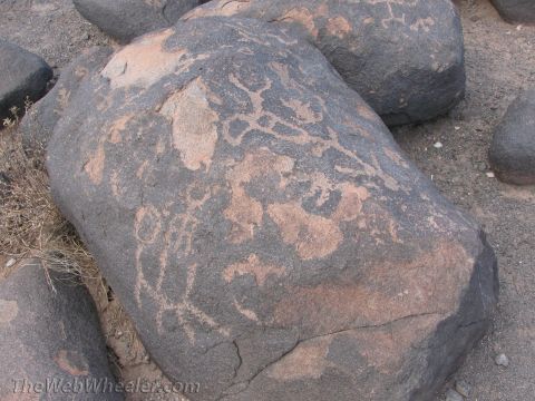 1996 Ford C-350 (Centurion Conversions) - Ancient petroglyphs are carved into a large rock in a desert landscape.