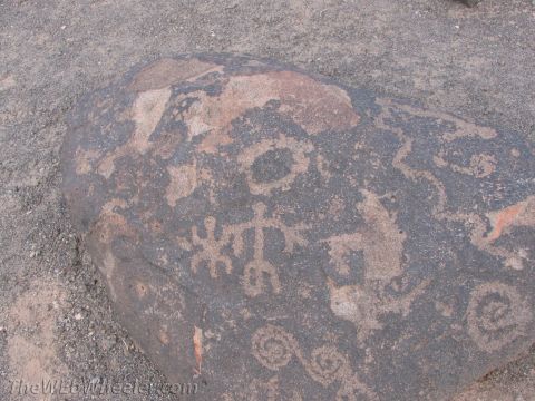 1996 Ford C-350 (Centurion Conversions) - Ancient petroglyphs carved into a dark rock surface, depicting various symbols and figures.