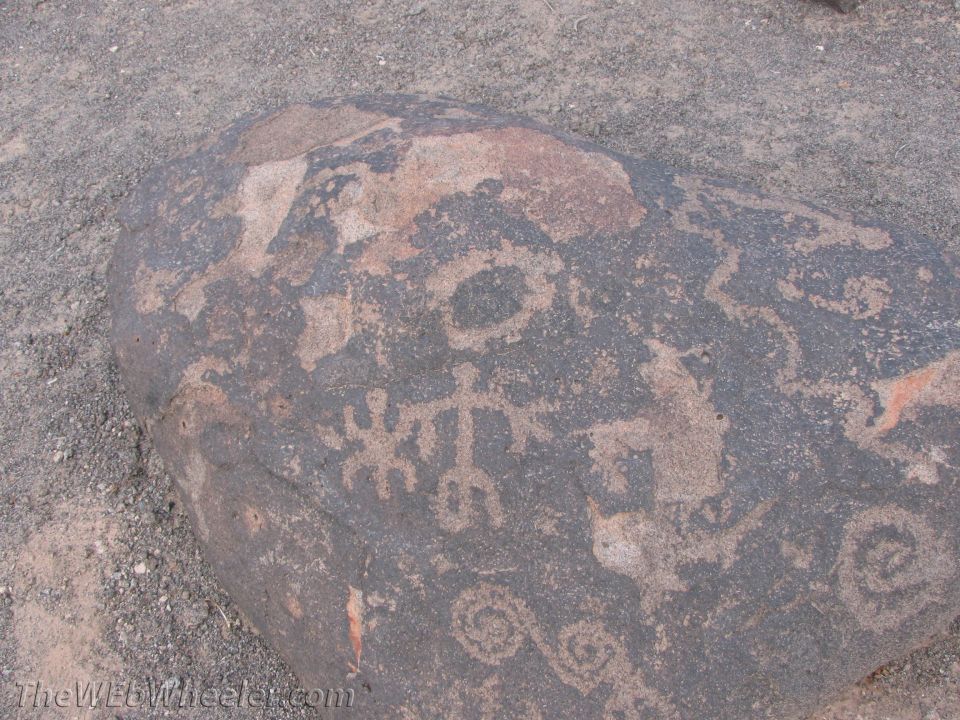 Rock with petroglyphs including human-like figures and spirals