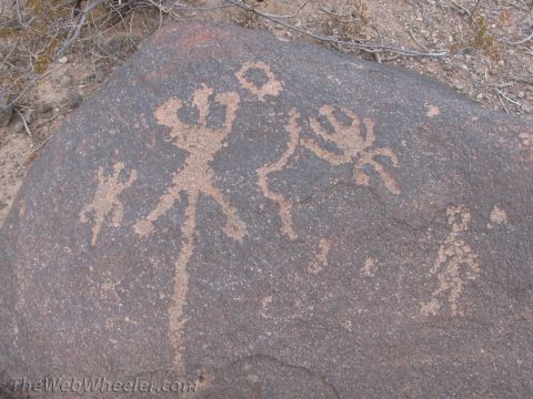 1996 Ford C-350 (Centurion Conversions) - Ancient petroglyphs are etched into the surface of a large rock in a desert landscape.