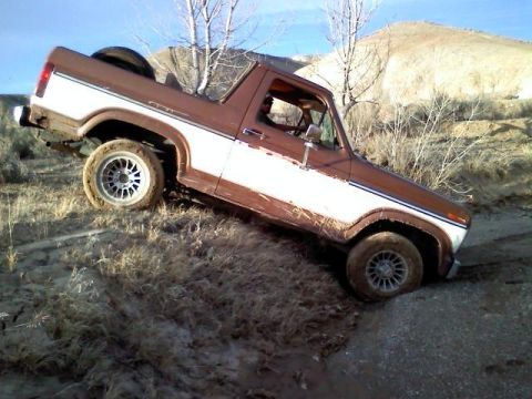 1985 Ford Bronco - This 1980s Ford Bronco is navigating a challenging off-road terrain.
