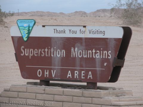 1996 Ford C-350 (Centurion Conversions) - Sign for Superstition Mountains OHV AREA in a desert landscape.