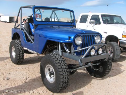 1996 Ford C-350 (Centurion Conversions) - A bright blue Jeep, modified for off-road use with a prominent roll cage, sits beside a white pickup truck.