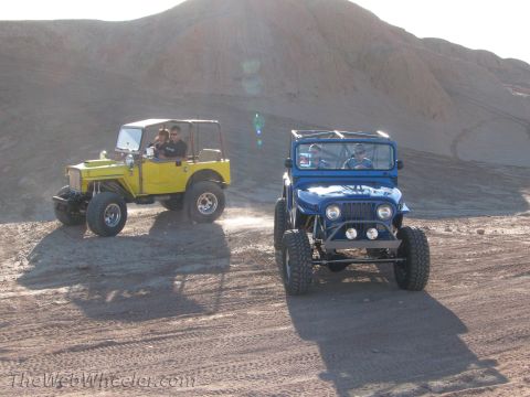 1996 Ford C-350 (Centurion Conversions) - Two modified jeeps drive on a dusty trail under a bright sun.