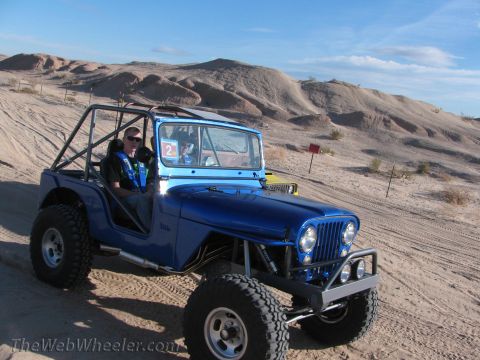 1996 Ford C-350 (Centurion Conversions) - Off-road Jeep navigates sandy terrain under a clear blue sky.