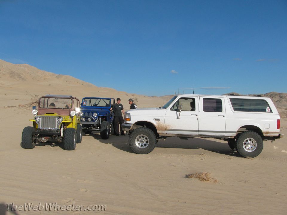 White extended cab pickup truck with four doors, lifted suspension, and large tires