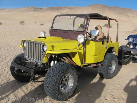 1996 Ford C-350 (Centurion Conversions) - A yellow jeep with a brown top and roll cage sits on sand dunes, with another vehicle in the background.