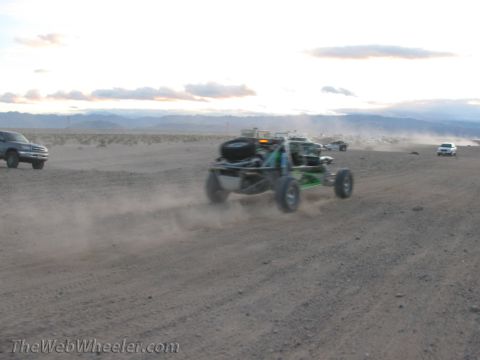 1996 Ford C-350 (Centurion Conversions) - Multiple vehicles traverse a dusty desert landscape under a cloudy sky.