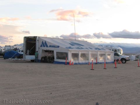 1996 Ford C-350 (Centurion Conversions) - A large tent is set up in a dusty outdoor area with several vehicles visible.