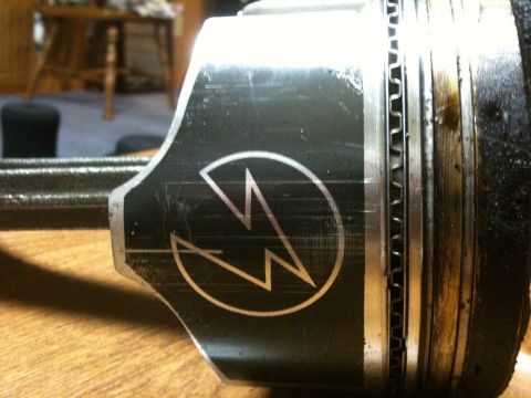 1972 Ford Ranchero - Close-up of a piston with a distinctive lightning bolt emblem, resting on a table.